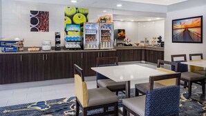 A hotel lobby with a seating area, a coffee station, and a large painting on the wall.