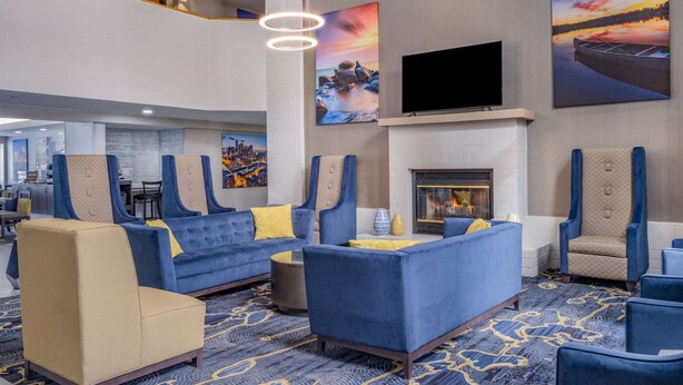 A lobby with blue sofas, a fireplace, and artwork on the walls.