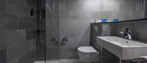 A modern bathroom with a glass-enclosed shower, a white toilet, and a sink with a mirror.