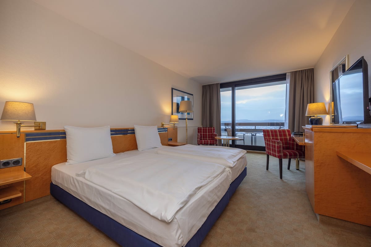 Une chambre d’hôtel avec un grand lit, un bureau, une chaise et une vue sur la ville.