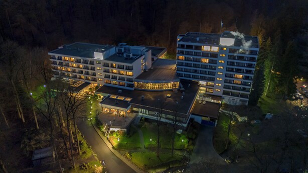 A modern hotel complex with multiple buildings, a central courtyard, and surrounding greenery.