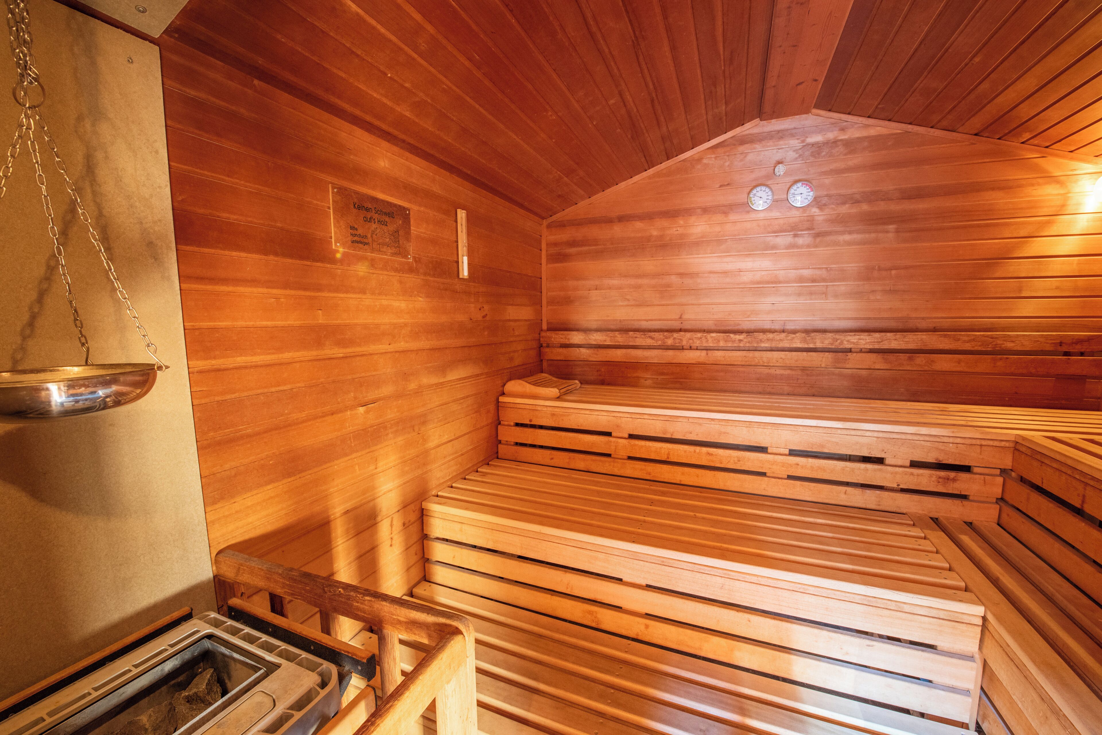 Eine Sauna mit Holzbänken und einem Metallbecken.