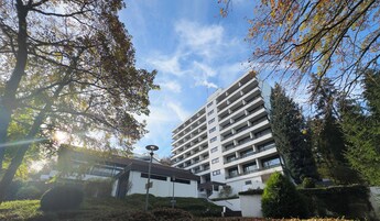 Un edificio moderno de varios pisos, rodeado de árboles y vegetación.