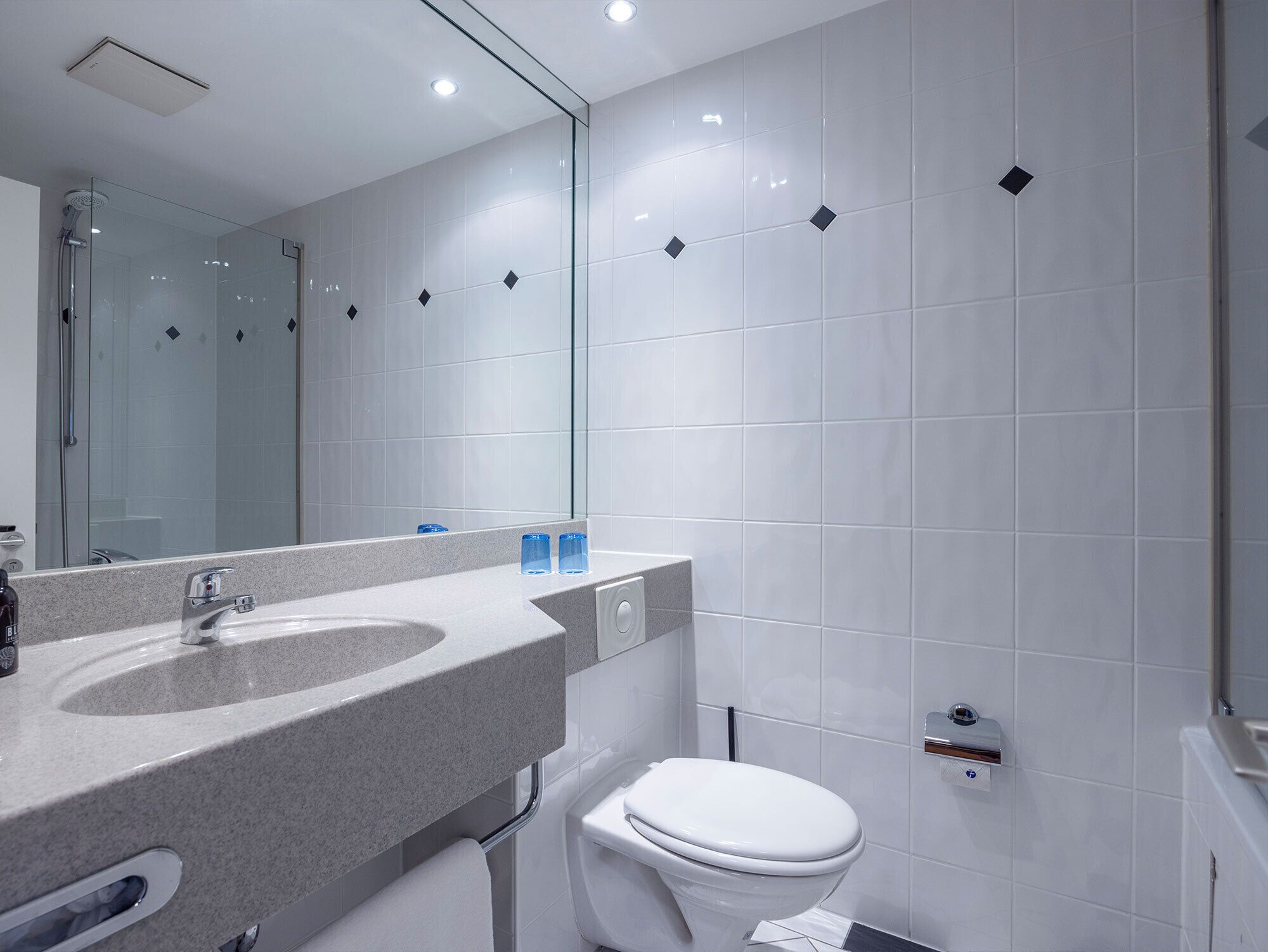 A modern bathroom with a large mirror, a sink, and a toilet.