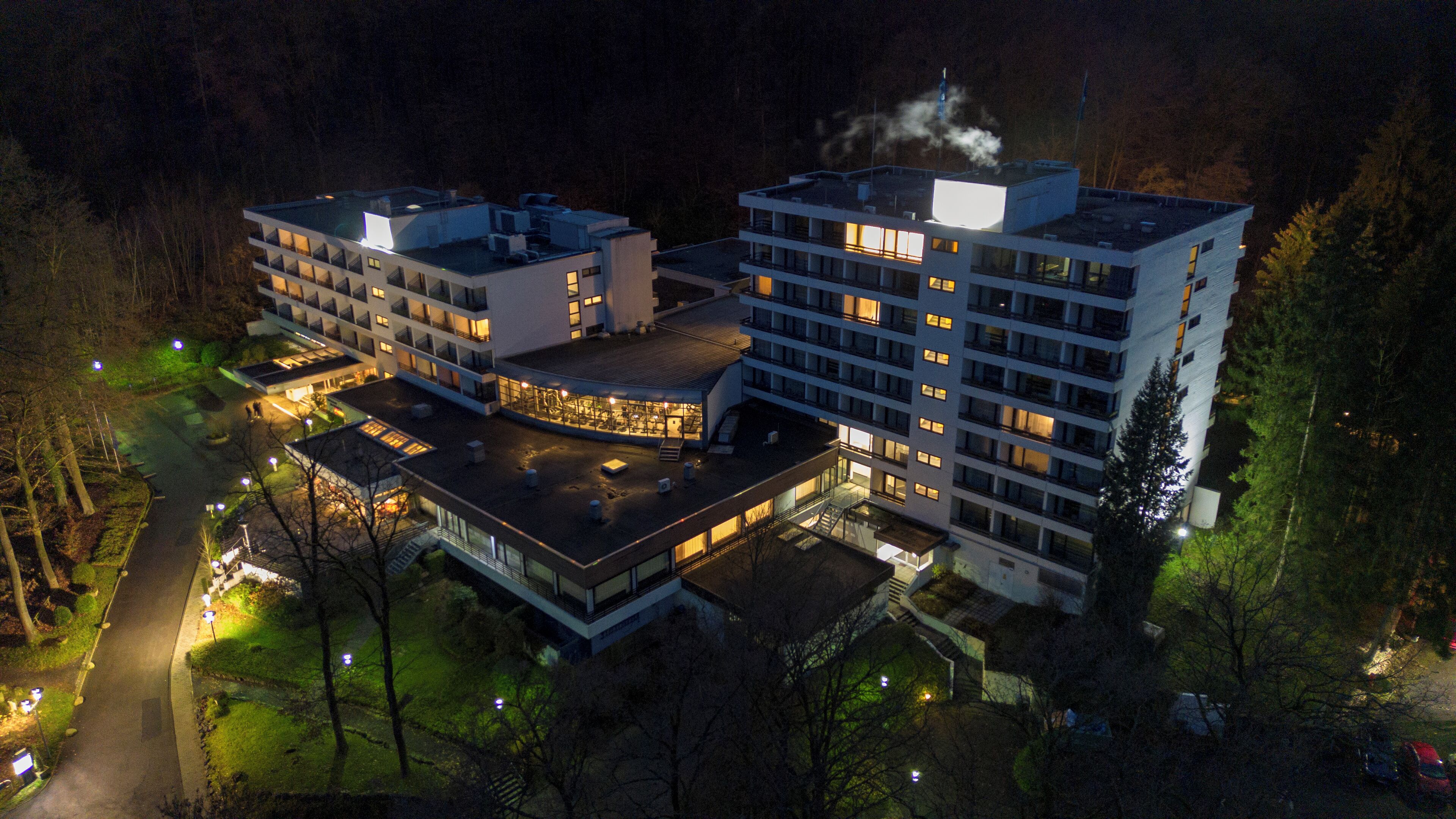 A modern multi-story hotel with a central courtyard, surrounded by trees.