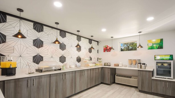 Una cocina moderna con decoración mural geométrica, electrodomésticos integrados y una barra desayunadora.