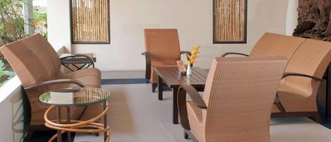 Un espace de détente moderne, avec des meubles en osier, une table en verre et un téléviseur à écran plat fixé au mur.