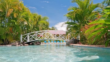 Relax by the serene pool, surrounded by lush tropical vegetation and a picturesque bridge.