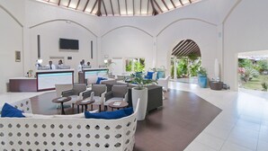 A spacious lobby with a high ceiling, a reception desk, seating area, and a view of the outdoor garden. - Radisson Grenada Beach Resort (St. George's)