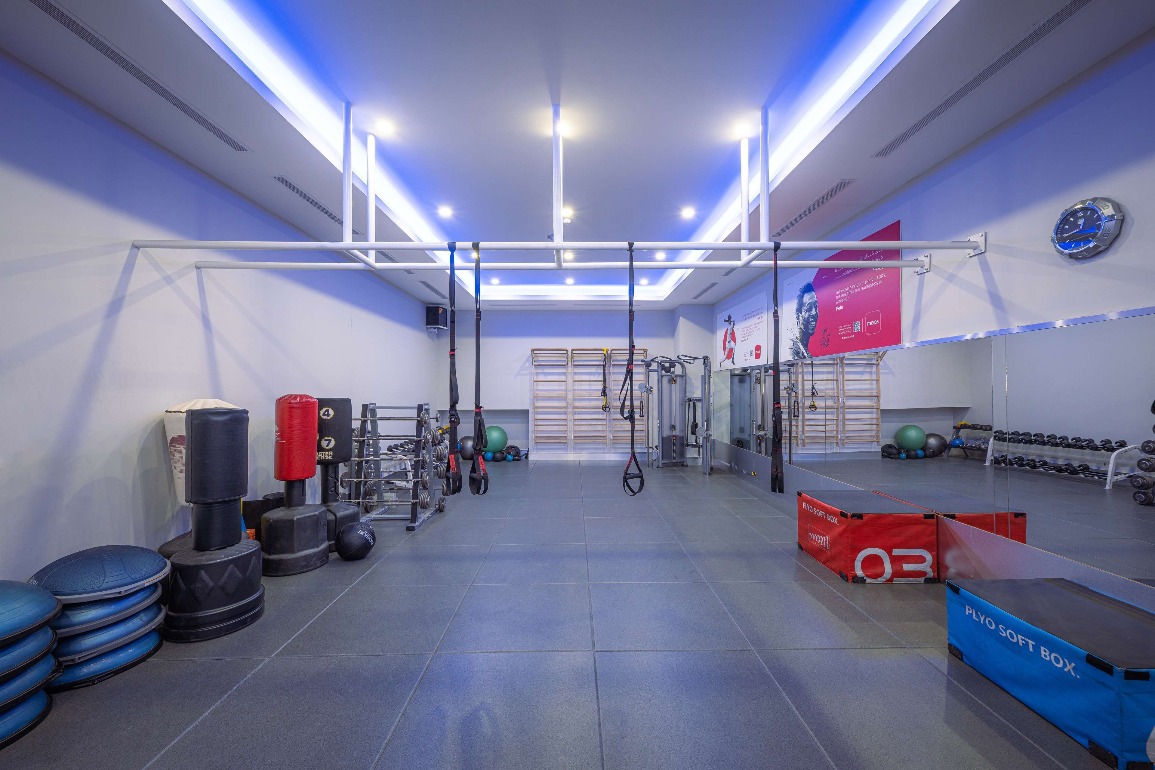 A gym with exercise equipment, a pull-up bar, and a mirror on the wall.