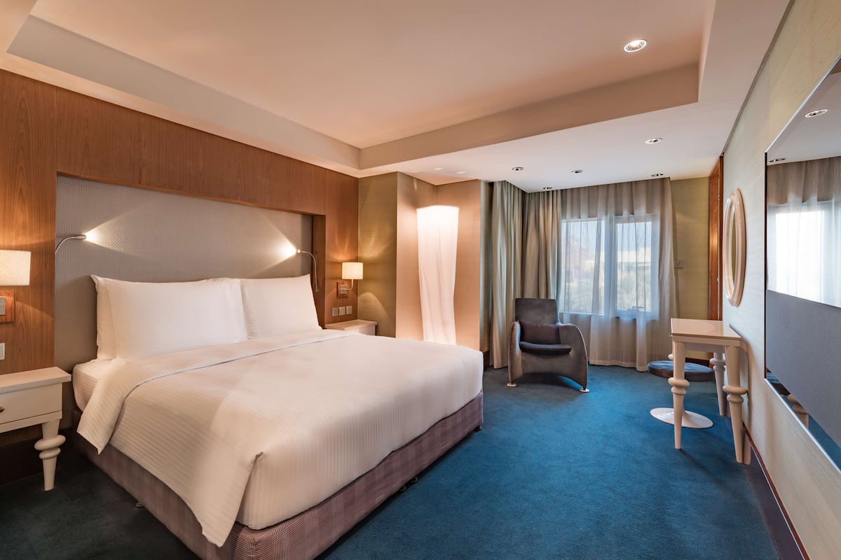 A hotel room with a large bed, bedside tables, a desk, and a chair.