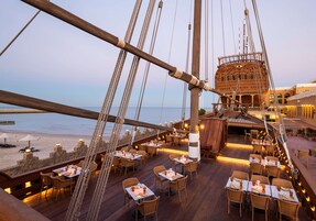 Comedor en un barco con mesas y sillas dispuestas para los huéspedes, con vistas al mar.