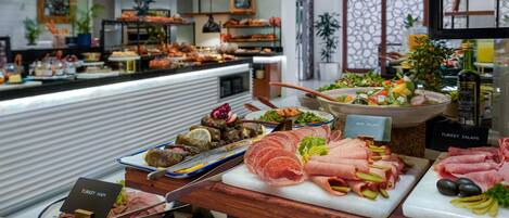 Un bufé con diversas carnes y ensaladas, incluyendo jamón de pavo, salami de res y salami de pavo.