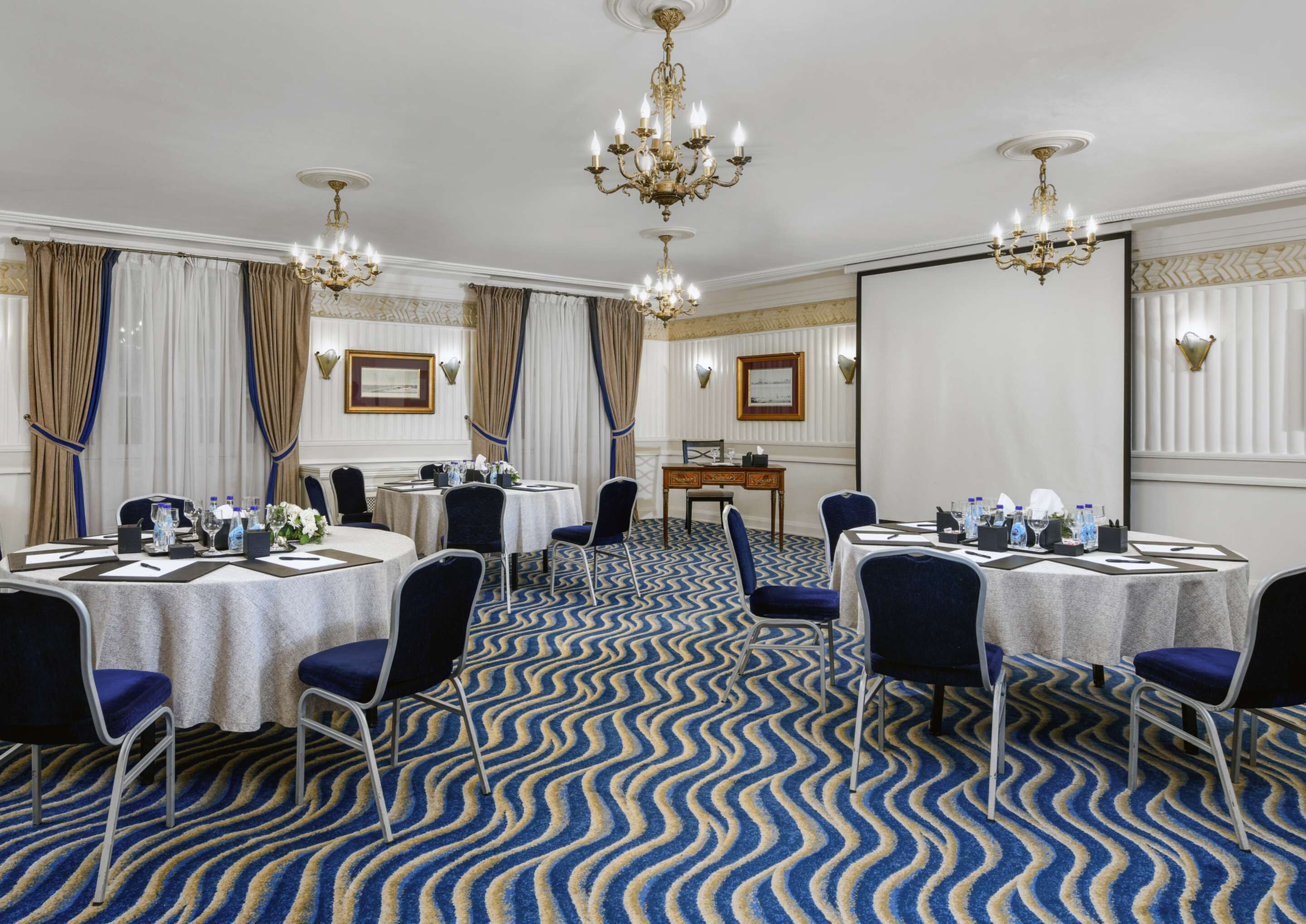 A conference room with round tables, chairs, and chandeliers.