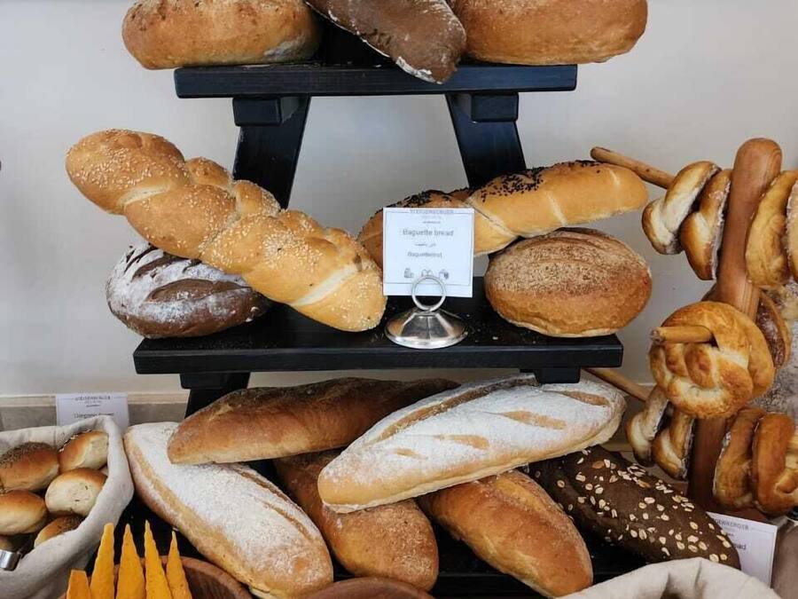 A display of various breads and pastries, including baguettes, croissants, and rolls, arranged on a tiered stand.