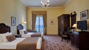 Habitació d'hotel amb dos llits, un escriptori, una televisió i vista al mar.