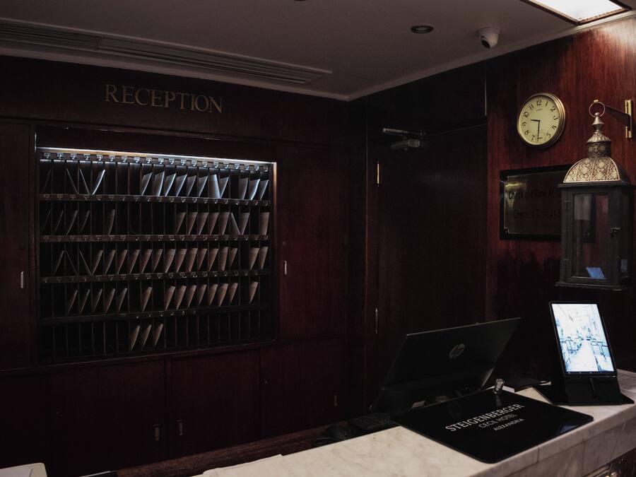 Uma área de recepção com balcão de check-in, um relógio de parede e um refrigerador de vinhos.