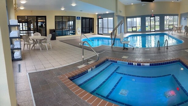 A pool area with a hot tub, seating, and a view of the outside.