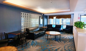 A lounge area with a sofa, chairs, a small table, and a patterned carpet.