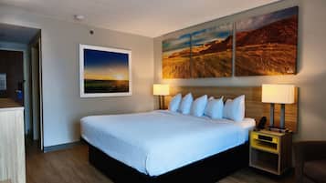 A hotel room with a large bed, two bedside lamps, a nightstand, and a wall-mounted painting.