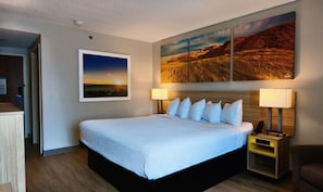 A hotel room with a large bed, two bedside lamps, a nightstand, and a wall-mounted painting.