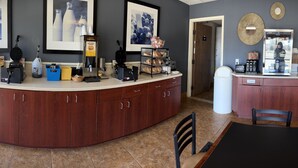 A kitchen area with a counter, microwave, toaster, coffee maker, and a trash bin.