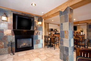 A stone fireplace with a flat-screen TV above it, surrounded by stone walls and wooden beams. - Best Western Torchlite (Wheatland)