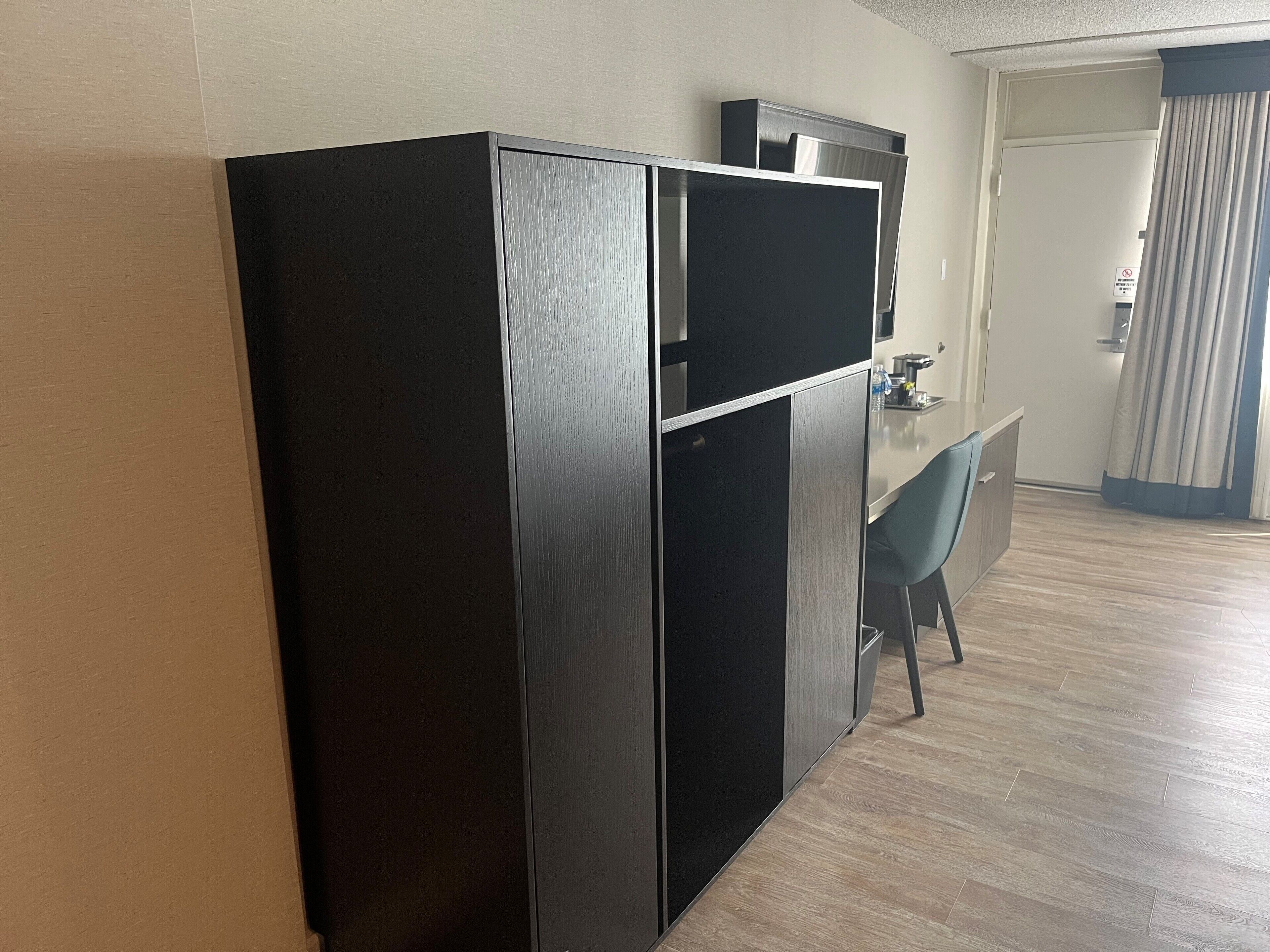 A modern kitchen with a black refrigerator, a coffee machine, and a small dining table with a chair.