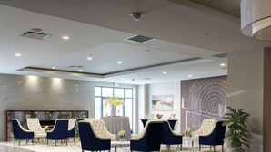 A modern lobby with a marble wall, a fireplace, and a seating area with blue and white chairs. - DoubleTree by Hilton Baltimore North - Pikesville (Pikesville)