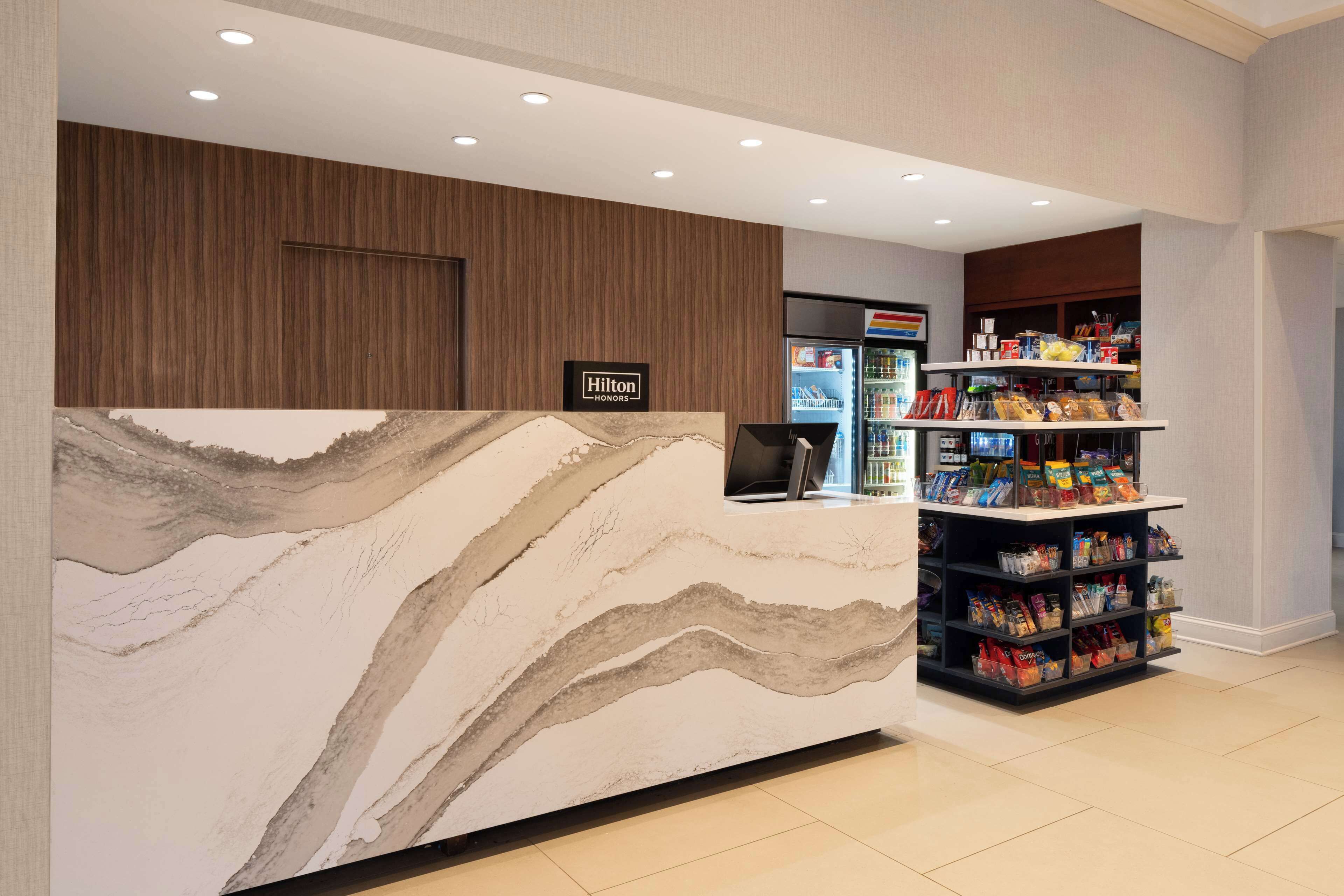 A hotel reception area with a marble counter, a minibar, and a vending machine.