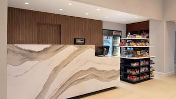 A hotel reception area with a marble counter, a minibar, and a vending machine.