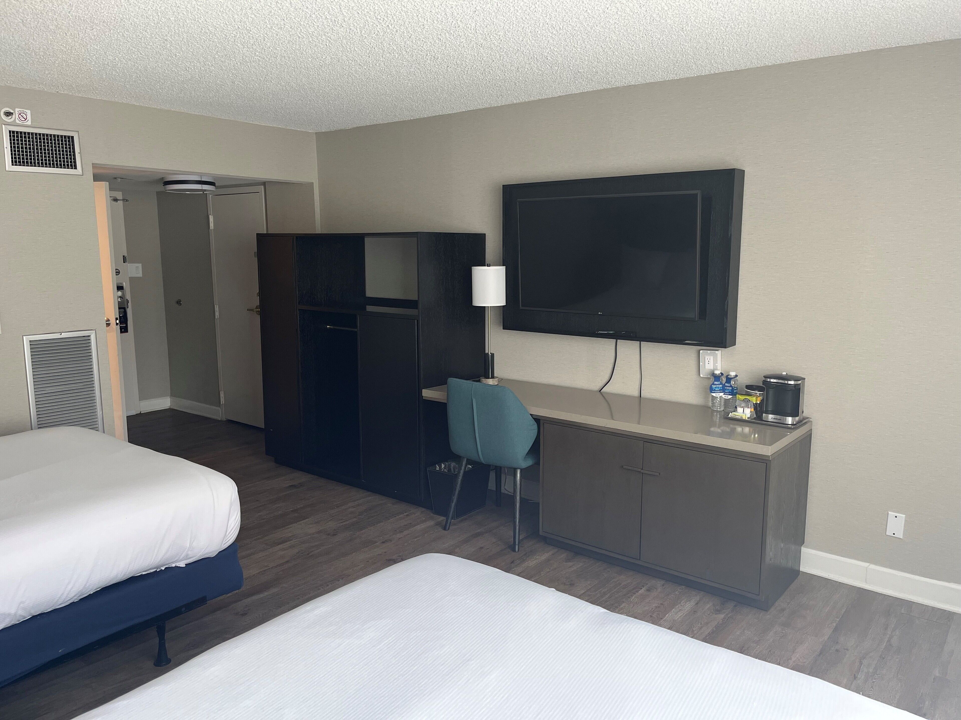 A hotel room with a bed, a desk, a TV, and a wardrobe.