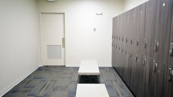 A hallway with lockers, a white door, and a bench.