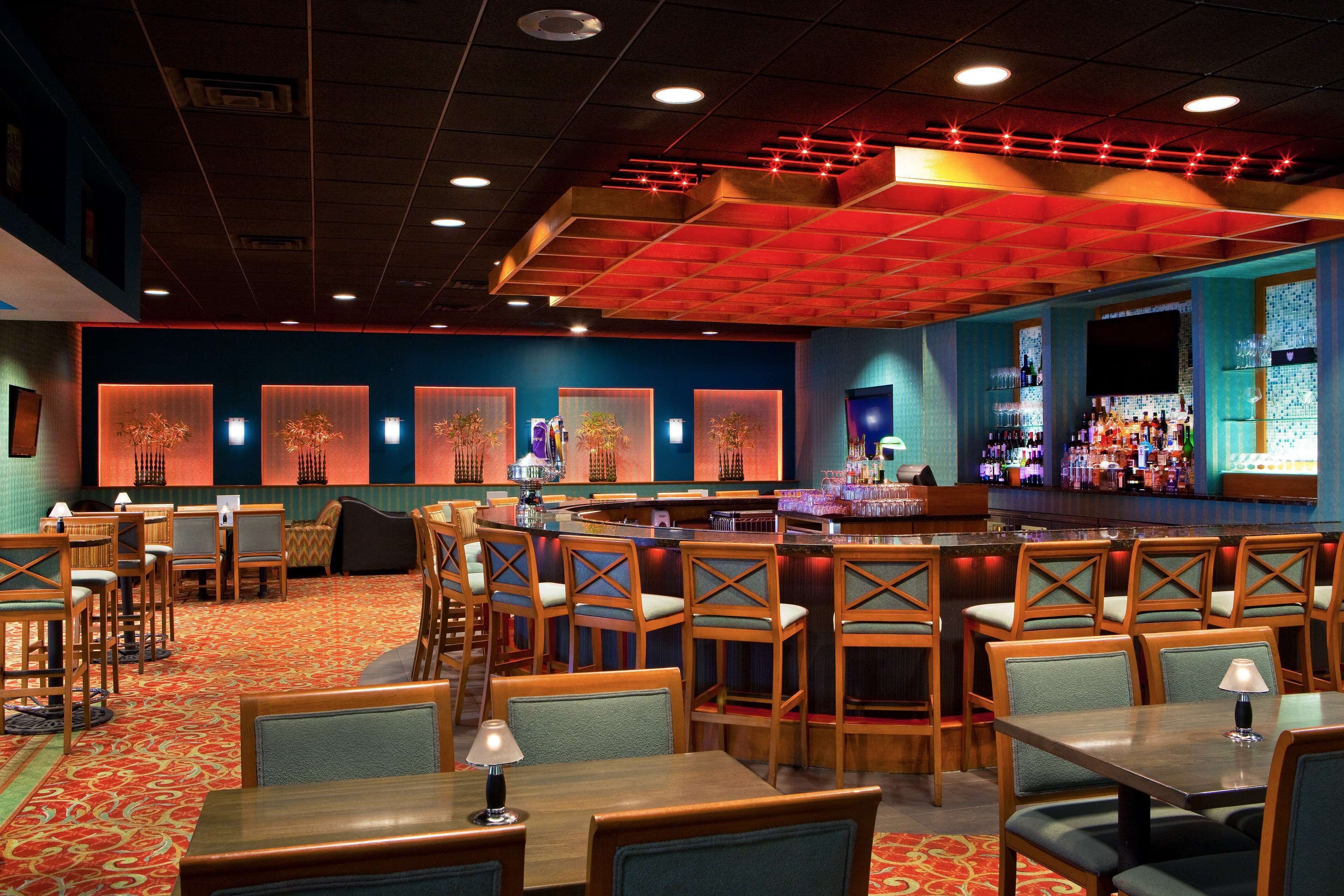 A restaurant with a bar area, multiple seating options including booths and tables, and a patterned carpet.