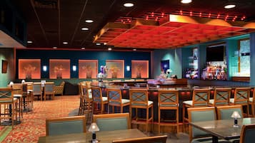 A restaurant with a bar area, multiple seating options including booths and tables, and a patterned carpet.