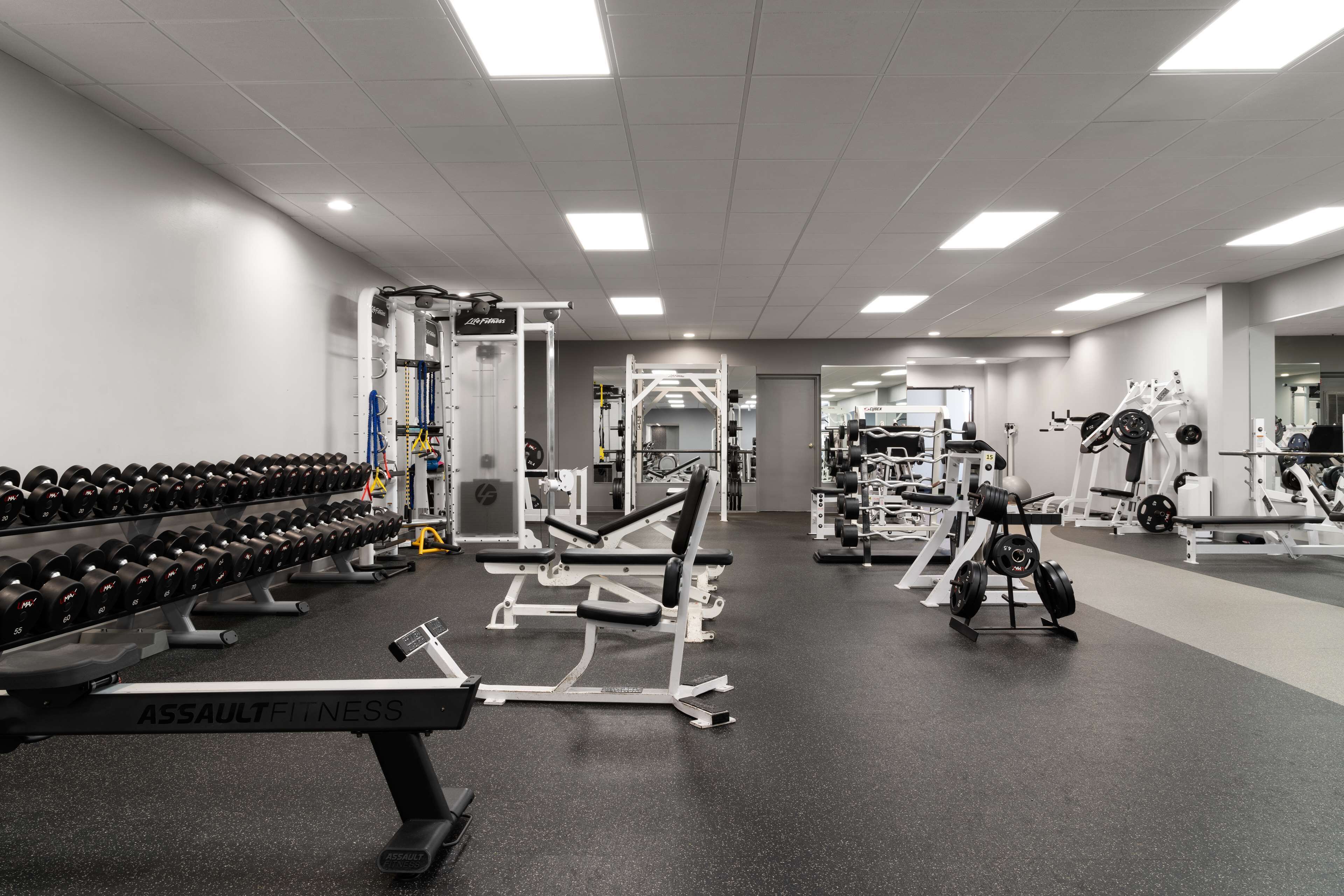 A gym with various exercise equipment, including dumbbells, benches, and weight machines.
