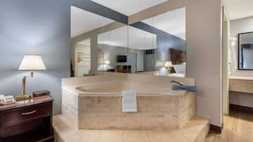 A modern bathroom with a large bathtub, a vanity with a mirror, and a telephone.