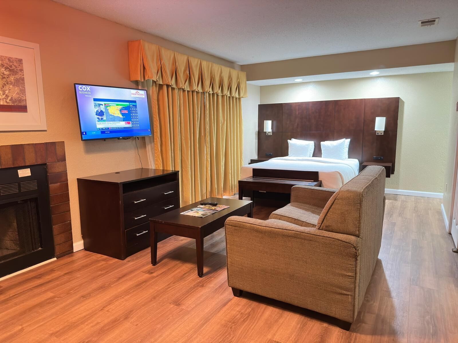 Una habitación de hotel con cama, televisión, sofá, mesa de centro y chimenea.