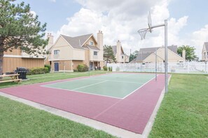 A basketball court with a red and green surface, surrounded by a white picket fence, and residential buildings in the background. - Hawthorn Extended Stay by Wyndham Wichita (Wichita)