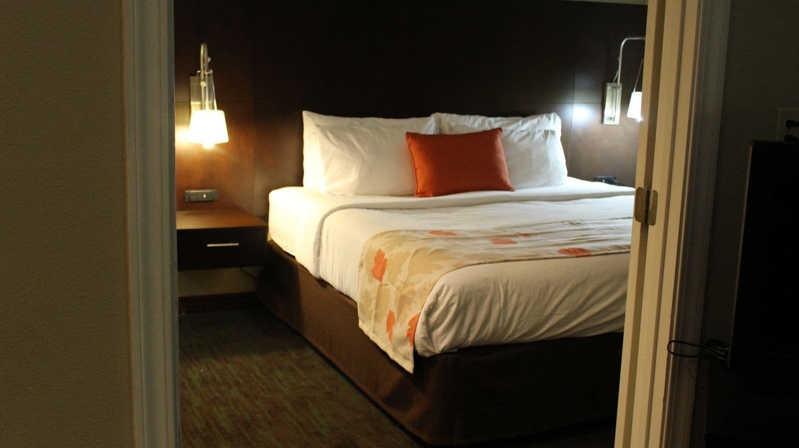 A hotel room with a bed, nightstands, and a lamp.