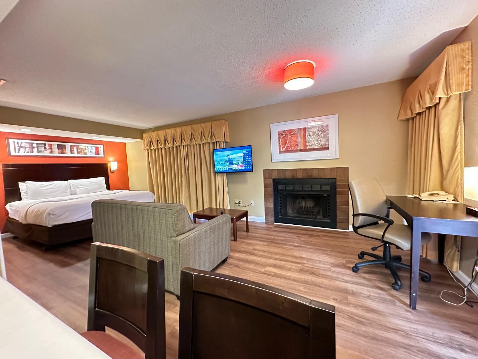 Ein Hotelzimmer mit Bett, Fernseher, Kamin und Schreibtisch mit Stuhl.