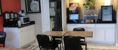 A compact kitchen with a dining area, equipped with a microwave, coffee maker, and a refrigerator.