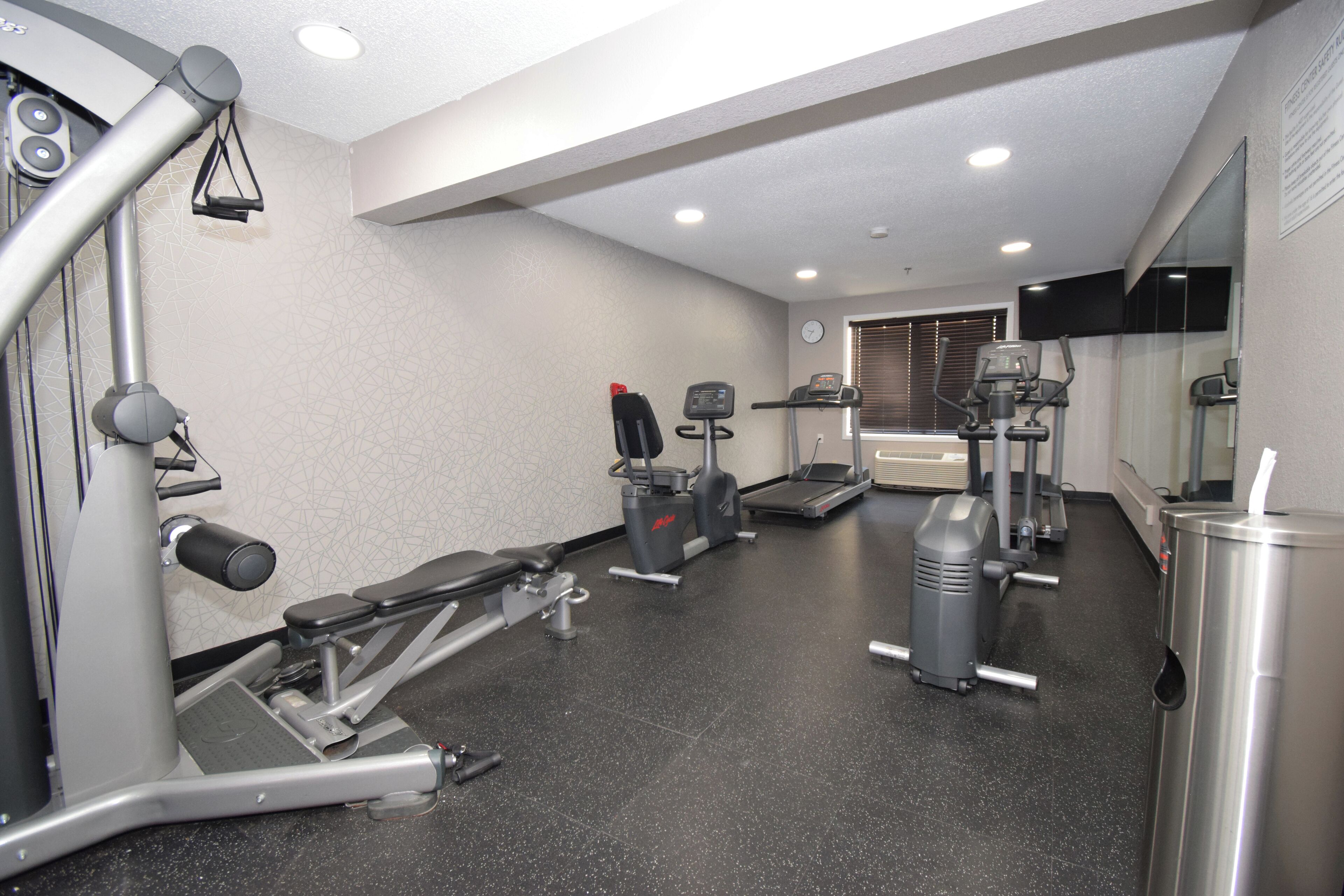 A gym with various exercise equipment, including a treadmill, stationary bike, and weight machines.
