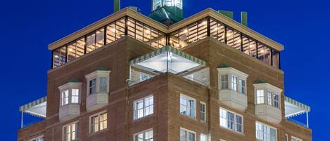 Een meerhoog gebouw met een opvallende toren en een balkon met een groene luifel.