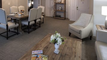 Una sala de estar con comedor, una mesa de centro con revistas y un centro de mesa floral.
