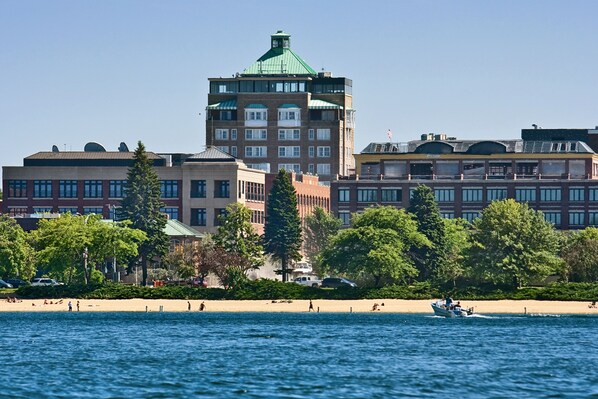 A waterfront hotel with a view of the water, a beach, and a cityscape in the background.