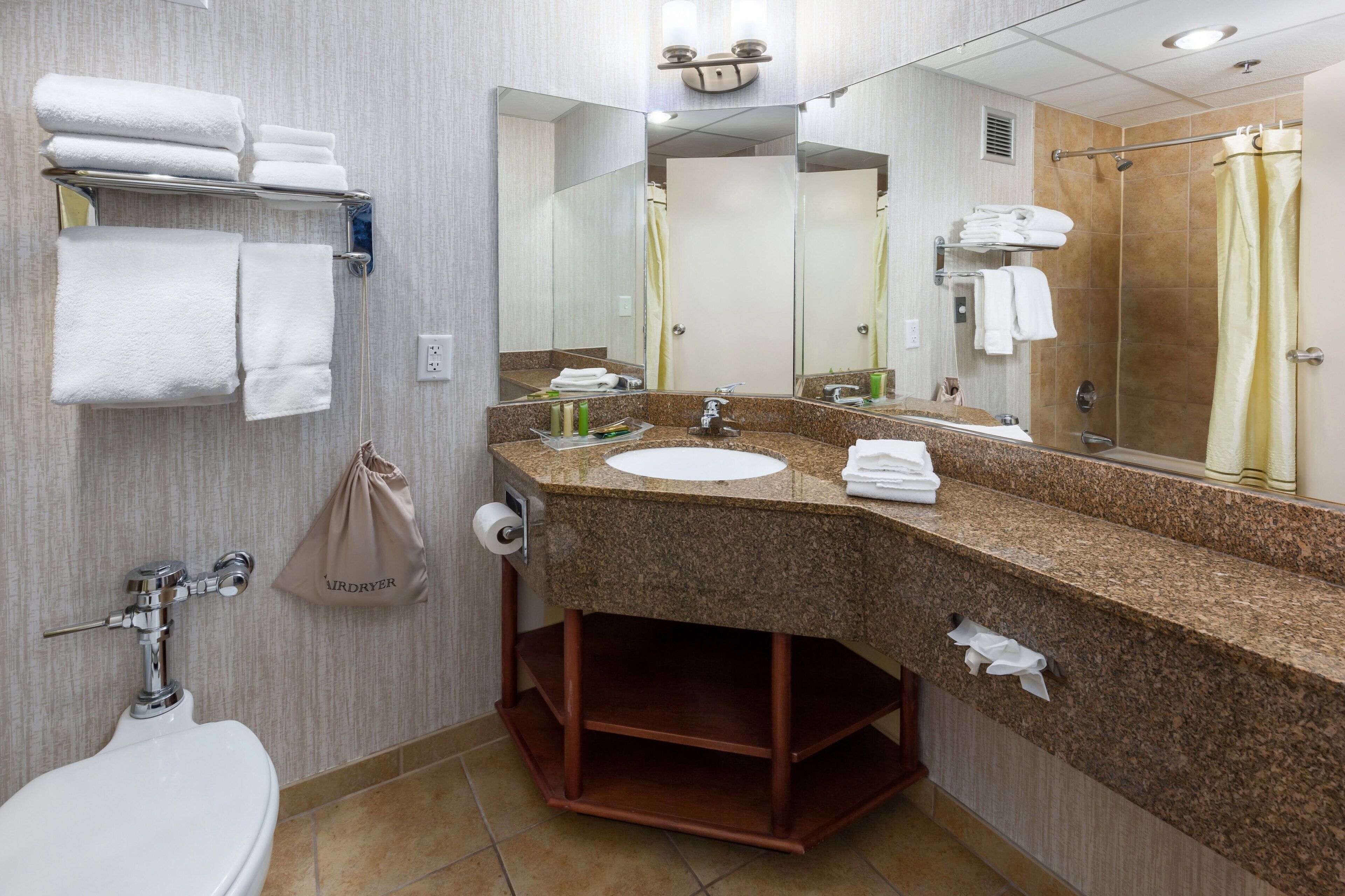 A bathroom with a sink, mirror, towel rack, and a bag of toiletries.