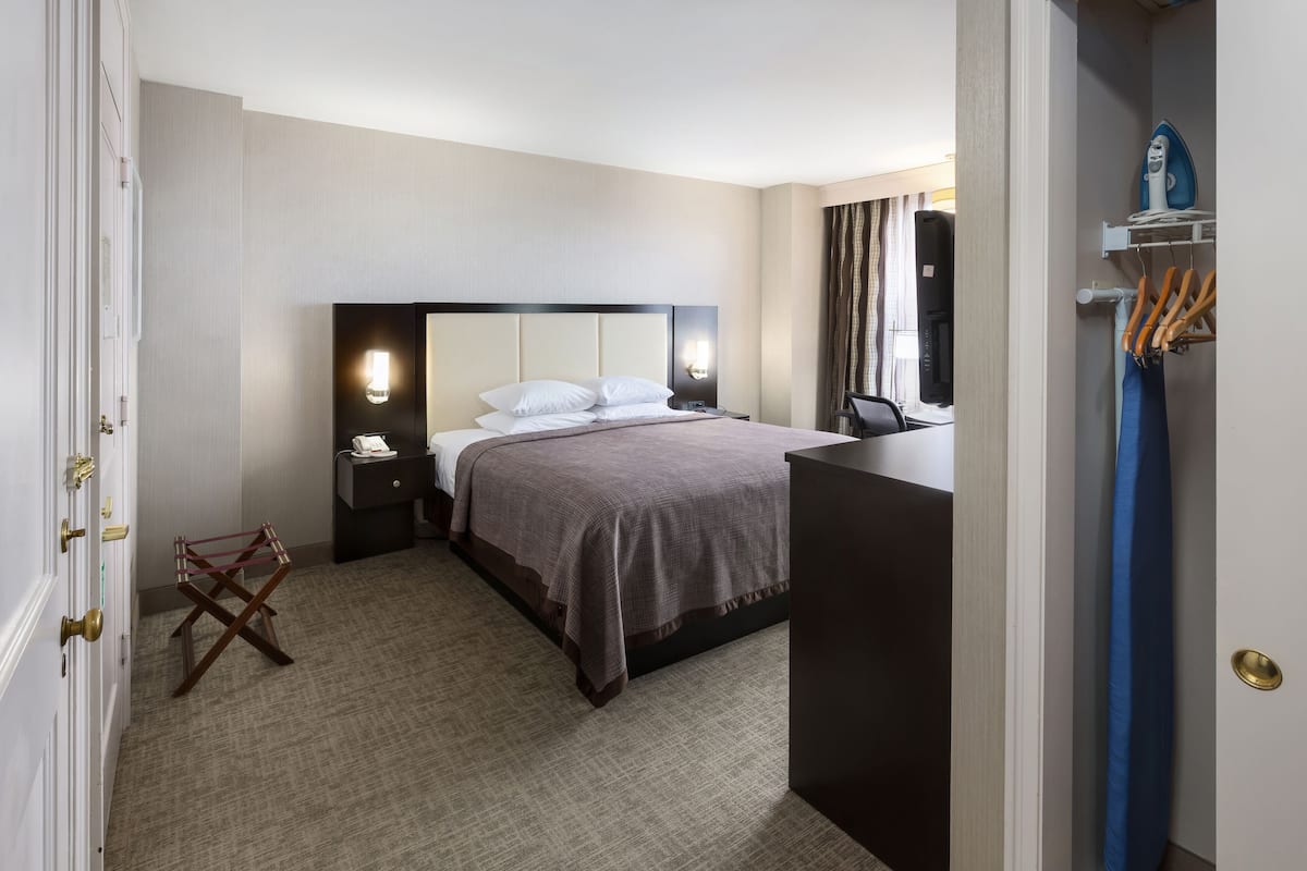Ein Hotelzimmer mit Bett, Nachttischen, Schreibtisch und Stuhl.