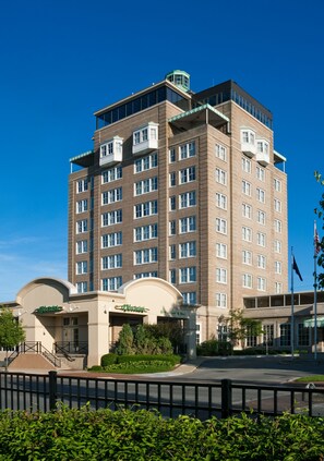 A multi-story hotel with a brick facade, large windows, and a central entrance with a curved canopy.