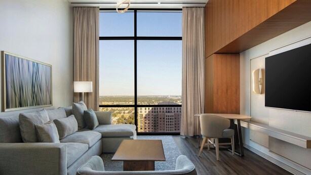 A modern hotel room with a large window, a sofa, a coffee table, a TV, and a desk. - The Westin Galleria Dallas (Dallas)